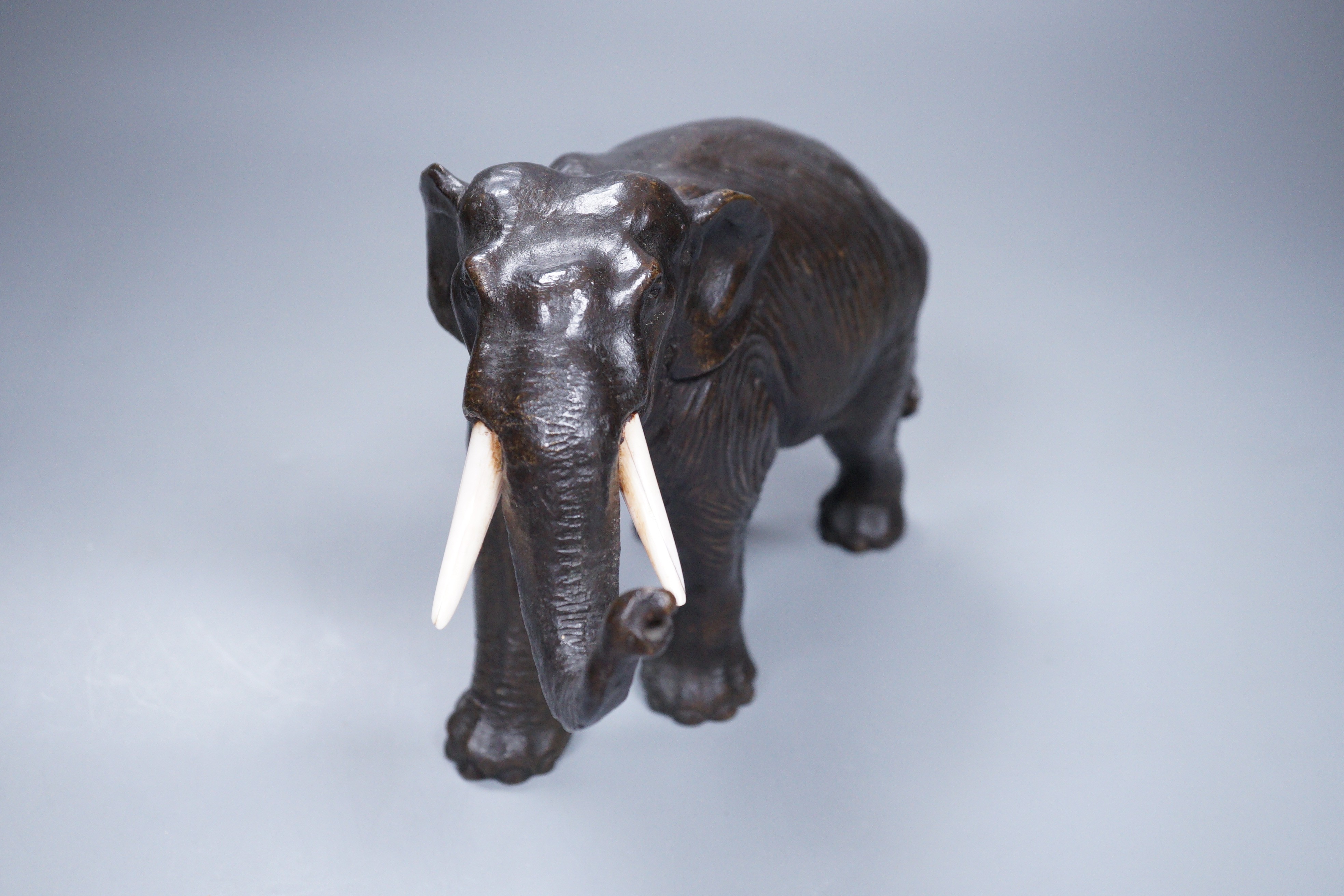 A Japanese Meiji period cast bronze model of an elephant, with ivory tusks, 17cm tall